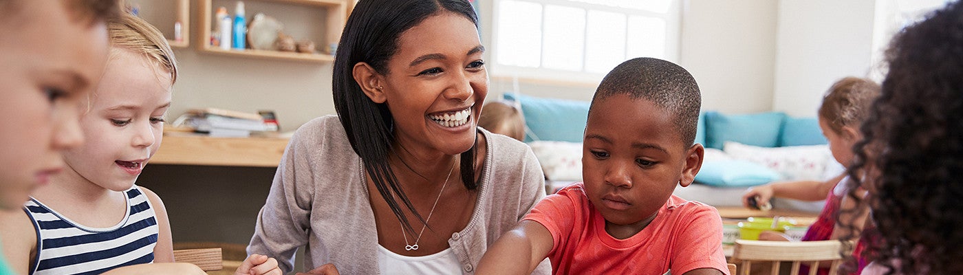 Elementary school teacher smiling as she works with students in class