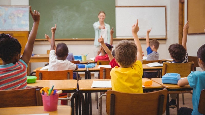 Elementary school teacher smiling as she works with students in class