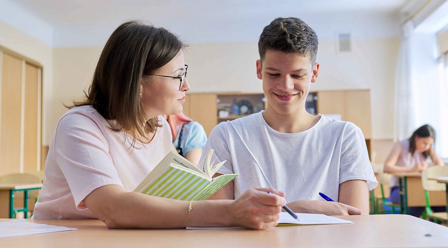 female teacher sitting at desk with student