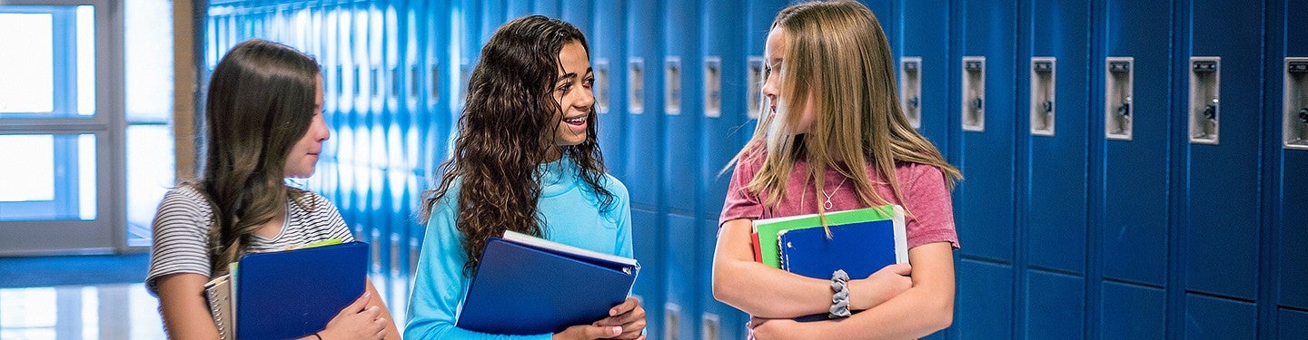 Three high school students walking in the hall and talking happily
