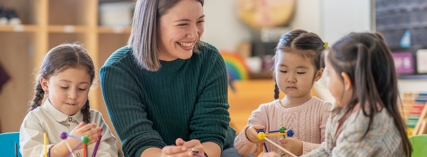 Teacher working with three small children in a classroom