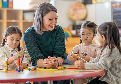 Teacher working with three small children in a classroom