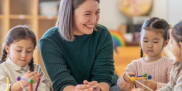 Teacher working with three small children in a classroom