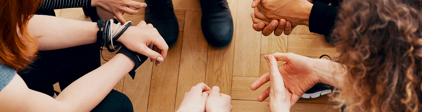 hands of students sitting together in a close circle