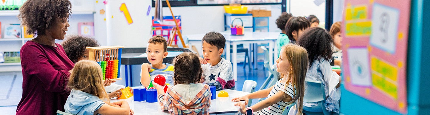 preschool teacher talking to children in school