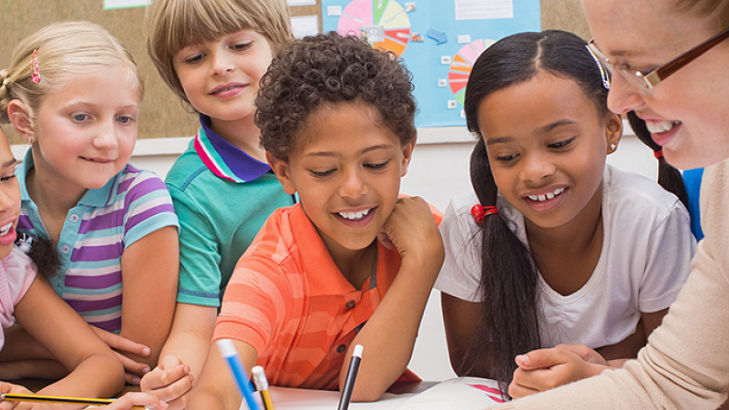 teacher showing students a lesson paper 