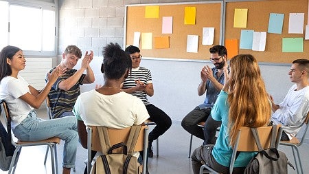 A group of high school students sitting in a circle with their teacher and having a discussion