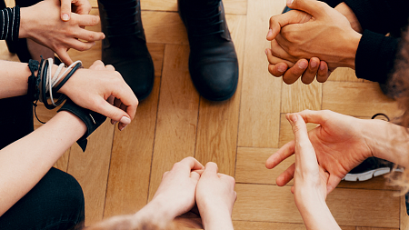 hands of students sitting together in a close circle